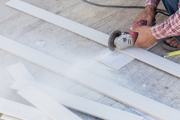 Wall Mural - carpenter hands using electric saw on wood at construction site