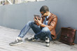 © Westend61 - Businessman sitting on wooden floor using mini tablet