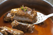 © Westend61 - Beef roulade on ladle, stew pot with sauce in the background