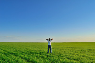 Wall Mural - young man on the summer green field under clear skies