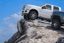 Big Rugged Trucks On The Edge Of A Rocky Cliff Ledge