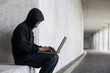 © Westend61 - Hacker with laptop sitting in an underground car park