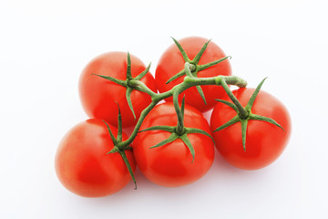 Looking down on five tomatoes with vine against white background