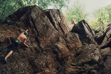 Poster - Sporty young man climbing on stone rock