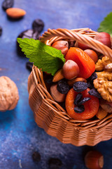 Wall Mural - Healthy concept: assortment of dry fruits and nuts on blue rustic background. Selective focus