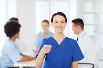 Poster - happy doctor over group of medics at hospital