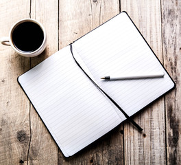 notebook with pen and coffee on old wooden table