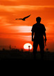 © napatcha - silhouette rear of man standing hand holding gun revolvers on sunset in the city background