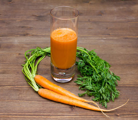 Carrot juice in glass on wooden table