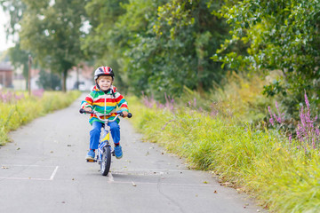 Poster - Kid boy in helmet riding his first bike, outdoors