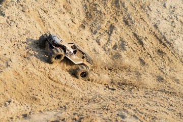 radio controlled monster truck performing a trick at high speed jumps over a large pile of sand. soft focus and beautiful bokeh