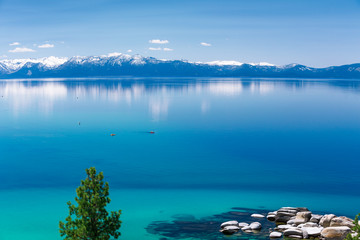 Canvas Print - Lake Tahoe calm turquoise waters with view on Sierra Nevada snowy peaks. There are two kayaks in the middle of the frame. 