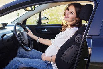 Pregnant happy young woman is sitting in black car