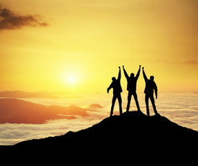 Wall Mural - Silhouettes of team on mountain peak. Sport and active life concept.