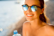 Woman drinking water from transparent bottle on the beach