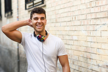 Poster - Young man in urban background listening to music with headphones