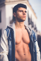 Wall Mural - Handsome young man with blue eyes posing in urban background