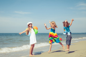 Sticker - Three happy children with balloons  dancing on the beach