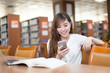 © zhu difeng - Asian beautiful female student using mobile phone in library