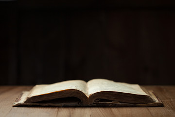 Wall Mural - Image of an old Holy Bible on wooden background in a dark space