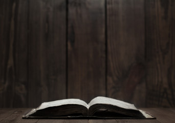 Image of an old Holy Bible on wooden background in a dark space