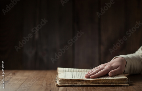 Fotografía woman reading the bible in the darkness over wooden table