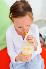 Wall Mural - Little girl drinking smoothies outdoors