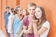 © petunyia - Group of happy young people standing near wall and kissing