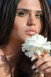 Pretty lady holding front of her face a big white roze