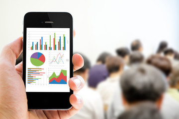 Poster - Close-up hand holding mobile phone with analyzing graph
