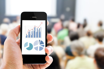 Poster - Close-up hand holding mobile phone with analyzing graph