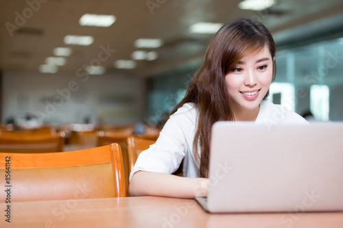 Foto Asian schöne Schülerin Studie in der Bibliothek mit Laptop