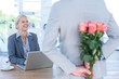 Businessman hiding flowers behind back for colleague