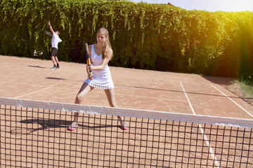 Wall Mural - Two athletes on tennis court.
Father and daughter starting new game on clay tennis field with bright back light sun flare