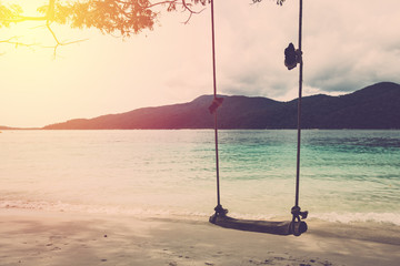 Wood swing in beautiful sand beach and sea. Vintage filter.