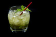A Mint Julep, the official drink of the Kentucky Derby, with fresh mint leaves, crushed ice, and a red stir stick with a black background. Drink is oriented on the left side of the photo.