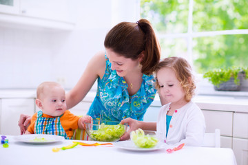 Wall Mural - Mother and children cooking in a white kitchen