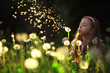 girl blowing a dandelion seeds flying