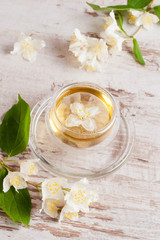 Glass cup of green tea with jasmine on wooden background