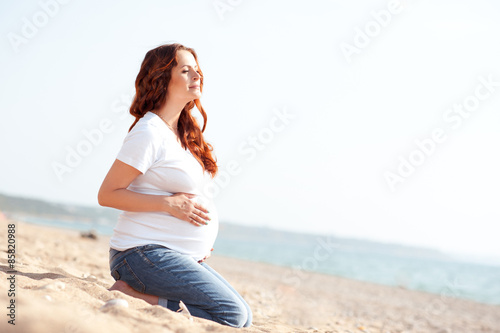 Fotografía Resting pregnant girl sitting at beach outdoors