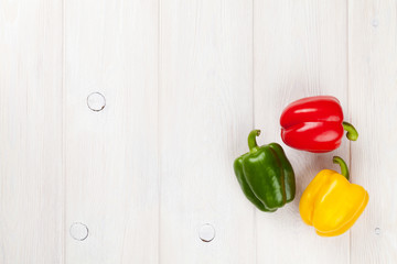 Colorful bell peppers on white wooden table