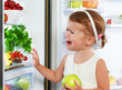 little girl child is crying and acting about fridge with fruit