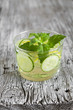 Lemonade with cucumber, lemon, mint and ginger in glass cups on a wooden surface