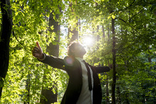 Businessman Standing With His Arms Outspread In Woodland