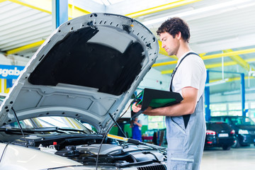 Mechanic with diagnostic tool in car workshop