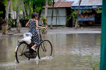 Burmese Girl Riding Bicycle In Flood Area