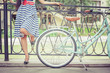Young girl dressed in a striped dress standing near fence, near vintage city bike at the park. Freedom woman with her happy vacation travel at European city, Paris