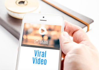 Poster - Close up hand holding smart phone with Viral Video word and icon