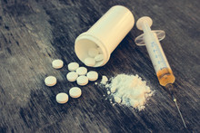 Drug Addiction On The Old Wooden Background. White Pill, Syringe And Heroin. Toned Image. 