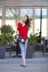 Young beautiful girl in blue jeans and red shirt on the backgrou